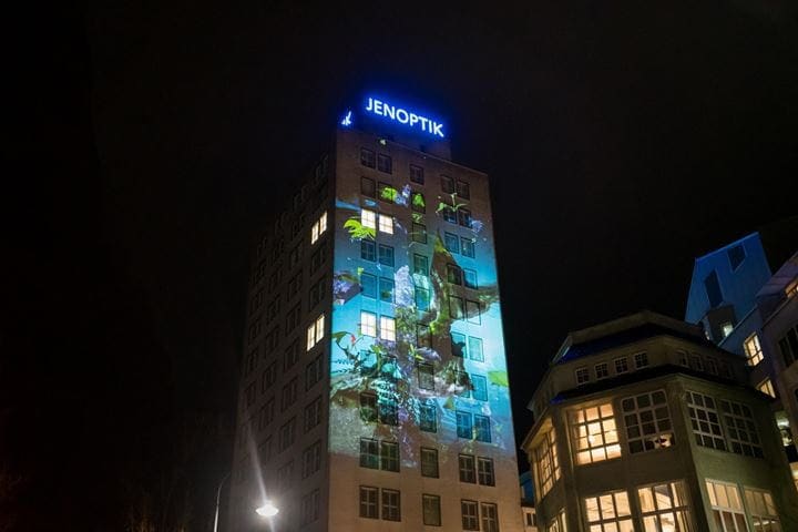 Jenoptik building at night with video mapping of Sabrina Ratté's "Florescendi" art