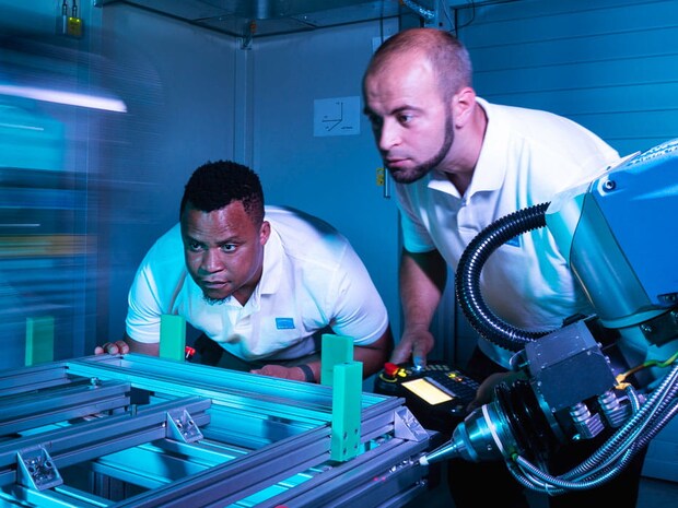 Two employees work on a machine