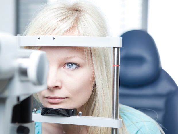 Optometry concept. Young woman having her eyes examined on a slit lamp.