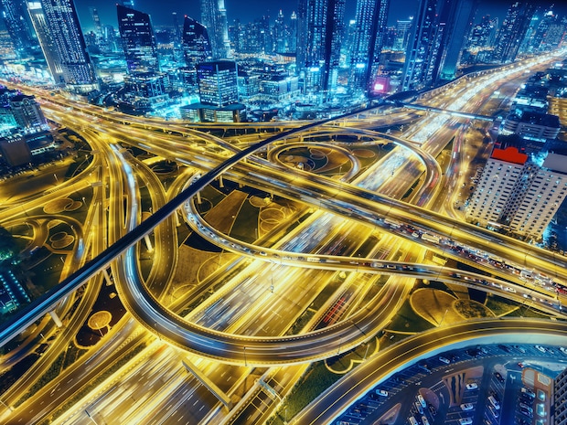 Aerial view of big highway interchange with traffic in Dubai, UAE, at night.