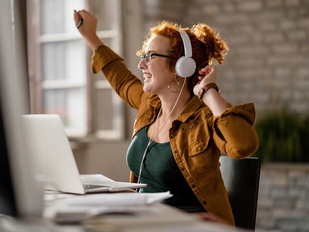 Woman sits at desk and listens to music while working 